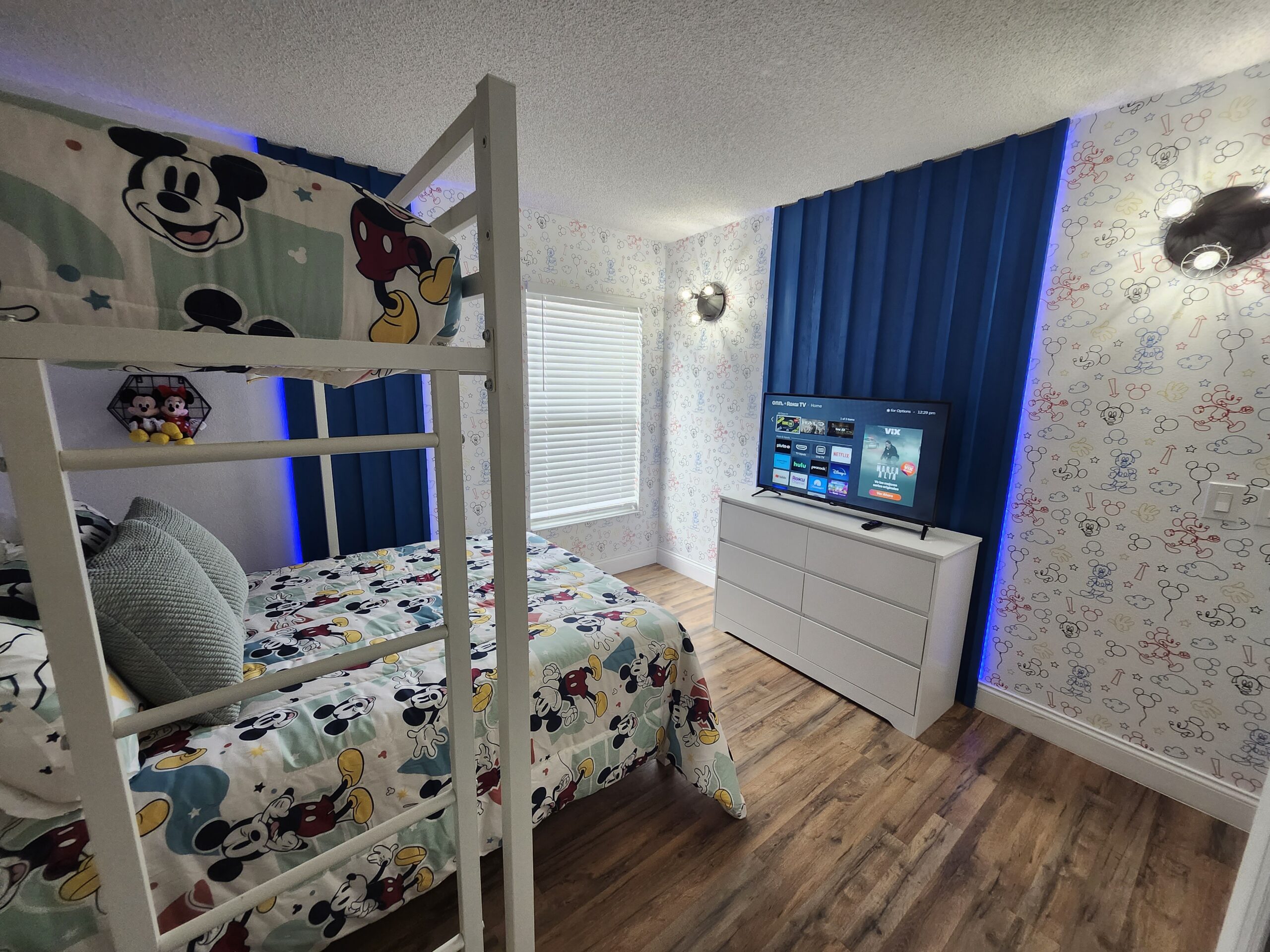 Mickey Mouse themed bunk bedroom in an Orlando vacation rental with blue LED accent lighting and character wallpaper
