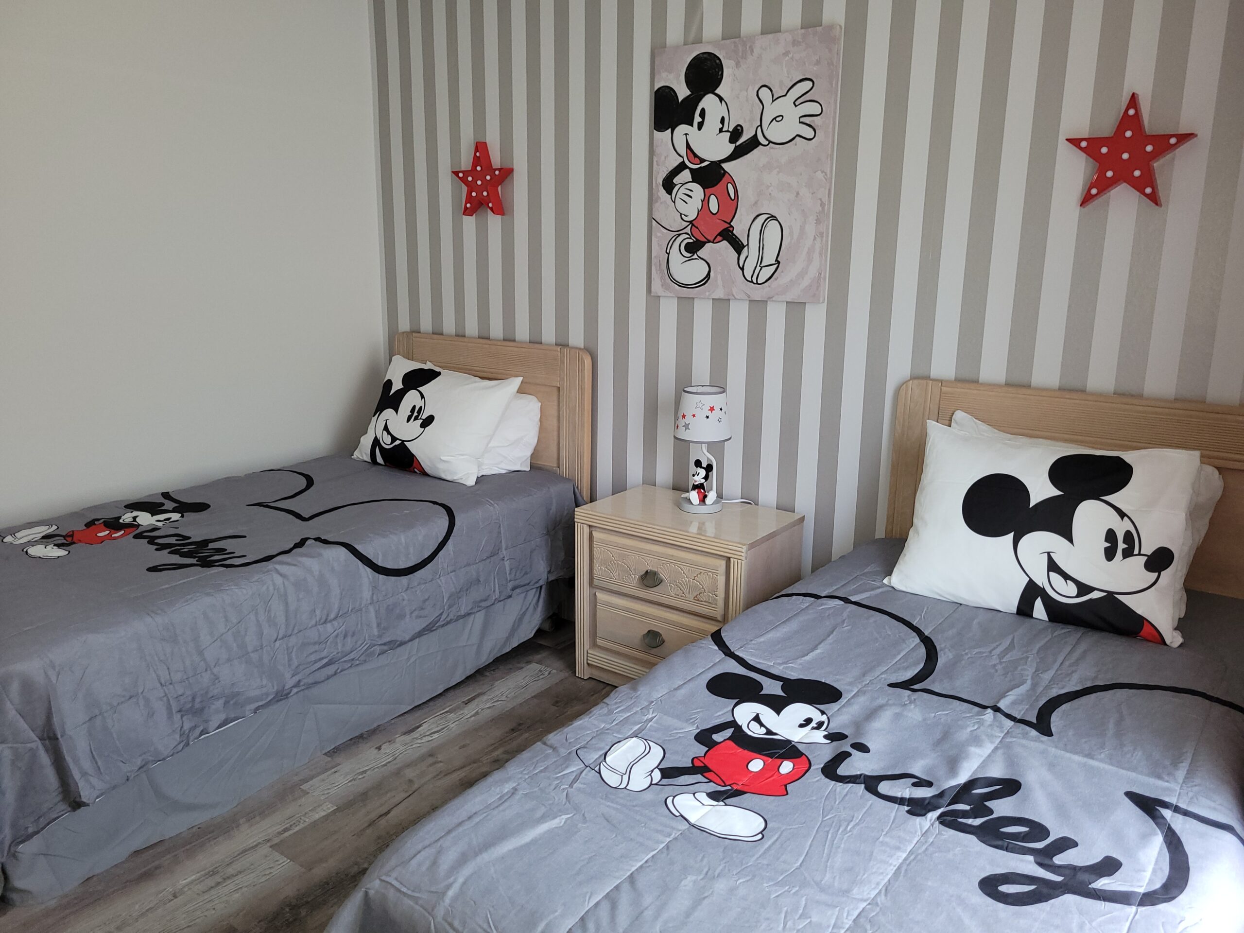 Mickey Mouse themed twin bedroom in an Orlando vacation rental with striped wallpaper, red star wall decor and painted Mickey canvas art