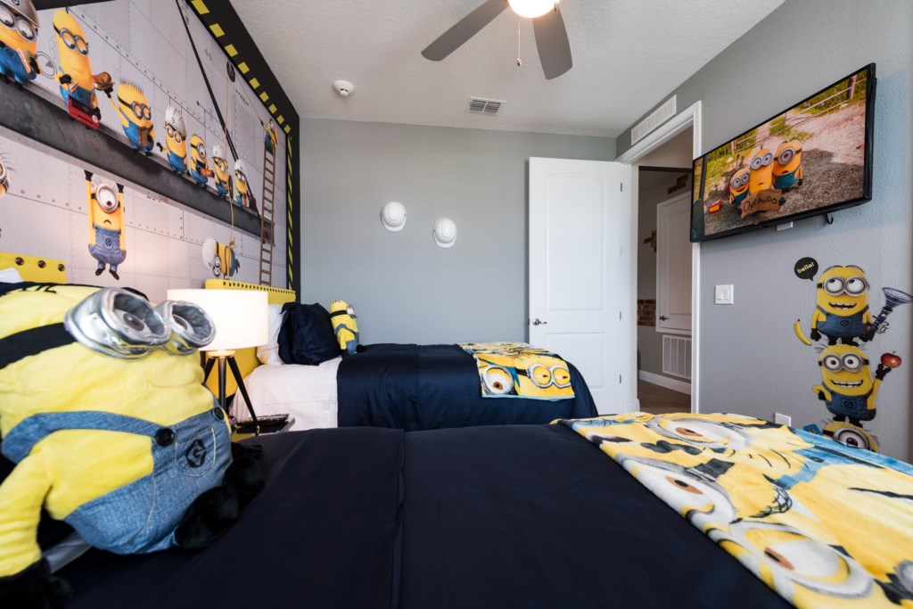 Minions themed bedroom in an Orlando vacation rental with construction-site mural, wall-mounted TV and yellow accents
