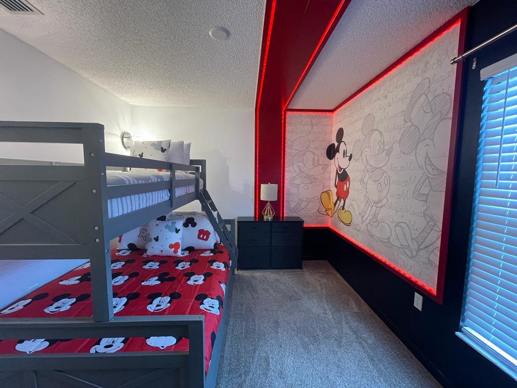 Mickey Mouse themed bunk bedroom in an Orlando vacation rental with red LED trim and a Mickey and Minnie line-art mural